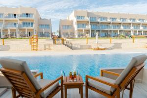 a resort with a swimming pool and two chairs and a table at Diamond Beach By Pearl Resort in Quseir