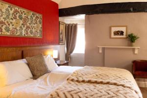 a bedroom with a white bed with a red wall at The bucks head in Church Stretton