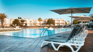 a swimming pool with lounge chairs and umbrellas at BLUESEA Bahía de Lobos in Corralejo