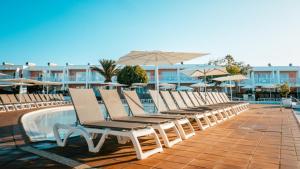 a row of lounge chairs next to a swimming pool at BLUESEA Bahía de Lobos in Corralejo
