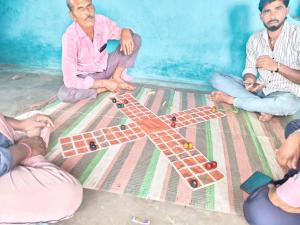 a group of men sitting on the floor playing with a toy airplane at Balendra Kumar in Tarahti