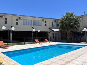 a swimming pool with two chairs and a building at Soleado Apart Hotel in San Rafael
