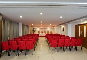 a conference room with red chairs and a stage at Hotel Indraprastha Kozhencherry in Kozhancheri