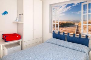 a bedroom with a bed and a window with a beach view at Affitta Camere di Berenice in Porto Azzurro