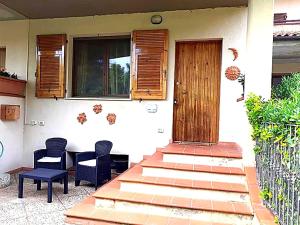 a house with two chairs and a table and a door at Affitta Camere di Berenice in Porto Azzurro