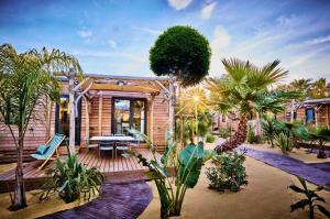 a house with a wooden deck with palm trees at Camping Les Sables d'Or in Cap d'Agde