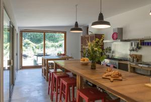 a kitchen with a large wooden table and red stools at Hangar Project in Saint-Michel-Escalus