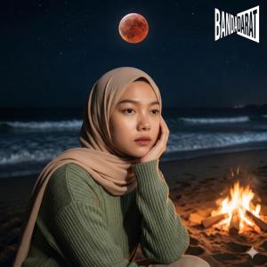 a woman sitting on the beach next to a fire at Bandardarat in Manado