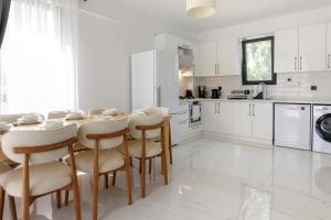 a white kitchen with a wooden table and chairs at Holiday Villa Lena in Köyceğiz