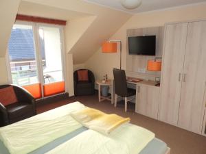 a bedroom with a bed and a desk and a tv at Hus op de Diek in Böhl