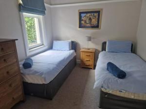 a bedroom with two beds and a dresser and a window at Airlie Gardens in Brodick