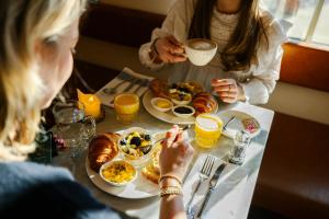 Twee vrouwen zitten aan een tafel te ontbijten. bij Hotel Bleecker by BHC in Bloemendaal