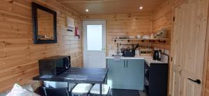 a small kitchen with a table in a wooden cabin at Mardi Gras, Upwell in Upwell