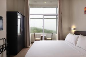 a hotel room with a bed and a large window at Oak Ray Misty Hills in Nuwara Eliya