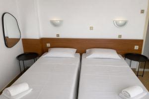 zwei Betten in einem Zimmer mit einem Spiegel und zwei Stühlen in der Unterkunft Pasiphae Self Hotel in Heraklion
