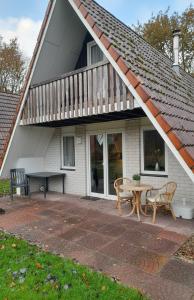 a house with a patio with a table and a deck at De Eekhoorn in Gramsbergen