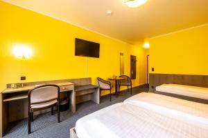 a yellow room with two beds and a table and chairs at Hotel Grunewald in Berlin