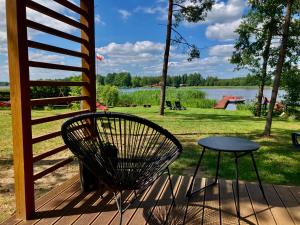 a chair and table on a deck with a view of a lake at Makosieje Resort-15m od brzegu,widok na jezioro,wi-fi in Makosieje