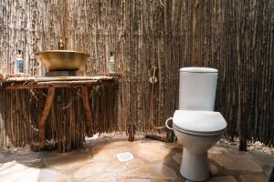 a bathroom with a toilet and a bowl on a wall at Bunduz Mara in Sekenani