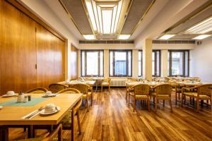 a restaurant with wooden tables and chairs and windows at Hotel Grunewald in Berlin