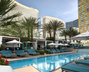 a swimming pool with blue lounge chairs and umbrellas at Waldorf Astoria Las Vegas in Las Vegas