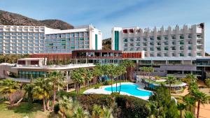 an aerial view of a resort with a pool and palm trees at Higuerón Hotel Málaga, Curio Collection by Hilton in Fuengirola