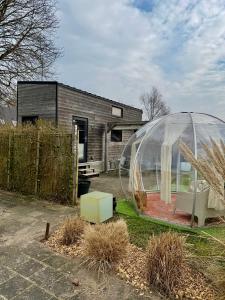 a glass igloo in front of a house at Tiny House Indy-Blue in Giethoorn