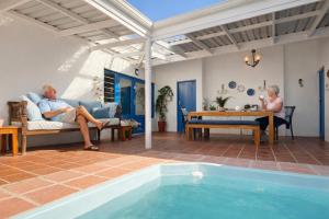an older couple sitting on a couch next to a pool at BlueSky Arniston Boutique Guesthouse in Arniston