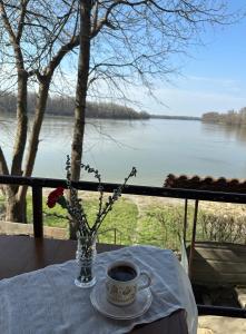 a table with a cup of coffee and a vase with flowers at Danube River Cottage - Bezdan in Bezdan +4 photos