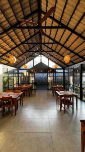 a restaurant with wooden tables and chairs and windows at Flower Valley Plantation Homestay in Munnar