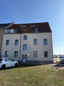 a white building with two cars parked in front of it at StayHere24 Maisonette-Wohnung mit großem Garten in Leipzig