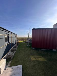 a yard with two buildings and a red building at Kolokemp pri súkromnom jazere Boldog in Senec