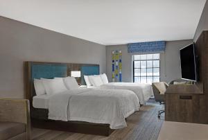 a hotel room with two beds and a flat screen tv at Hampton Inn Westfield in Westfield