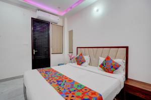 a bedroom with a large white bed with colorful pillows at FabHotel Metro Inn in Kānpur