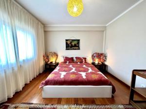 a bedroom with a bed with a red comforter at Villa Mar & Surf • Piscina privada in Atouguia da Baleia +40 photos