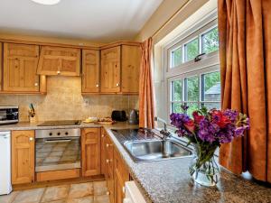 a kitchen with wooden cabinets and a vase of flowers on a counter at 2 Bed in Alford oc-92252 in Rigsby