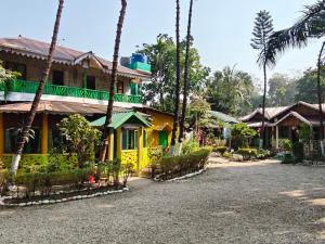 a yellow house with palm trees in front of it at Orchid Resort in Lataguri
