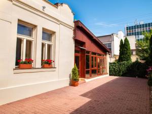 a white building with windows and potted plants on a sidewalk at Pribina Penzión in Nitra