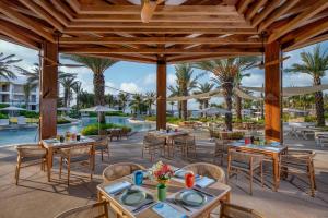an outdoor dining area with tables and chairs and a pool at Conrad Punta de Mita in Punta Mita