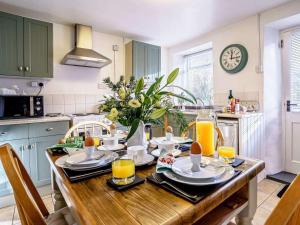 a kitchen with a wooden table with plates and orange juice at 2 Bed in Llandysul oc-79199 in Felindre