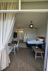 a bedroom with a bed and a desk and a couch at Ocean Daze Brookes Hill Suites - Beachfront Flat in Summerstrand