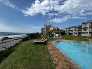 a swimming pool with a bench next to the beach at Ocean Daze Brookes Hill Suites - Beachfront Flat in Summerstrand