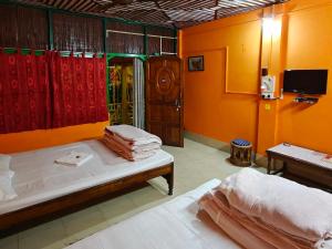 a bedroom with orange walls and a bed with towels at Orchid Resort in Lataguri