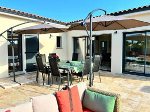 a patio with a table and an umbrella at Gîte Le 10 in Neuville-du-Poitou