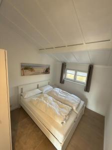 a white bed in a room with two windows at Dune Nest 233 - beautiful house near beach - up to 4 guests with garden, parking, WLAN in Bredene