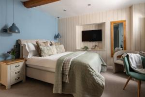 a bedroom with a bed and a tv and a chair at The Lansdowne Boutique Rooms with Breakfast - Adults Only in Bourton on the Water