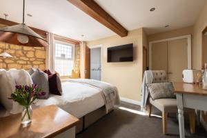 a bedroom with a bed and a desk and a television at The Lansdowne Boutique Rooms with Breakfast - Adults Only in Bourton on the Water