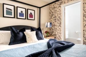 a bedroom with a bed with black and white pillows at The Lansdowne Boutique Rooms with Breakfast - Adults Only in Bourton on the Water