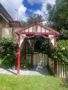 a red and white house with a white fence at Dees Rear Studio Room in Hazelbrook