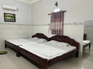 a bedroom with a large bed with white sheets at Nhà Nghỉ HOA LÝ in Chau Doc